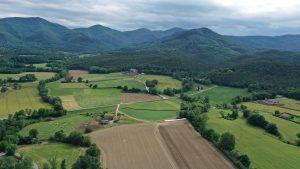 Vista aèria de camps a Sant Miquel en pirmer terme i muntanyes al fons de la imatge